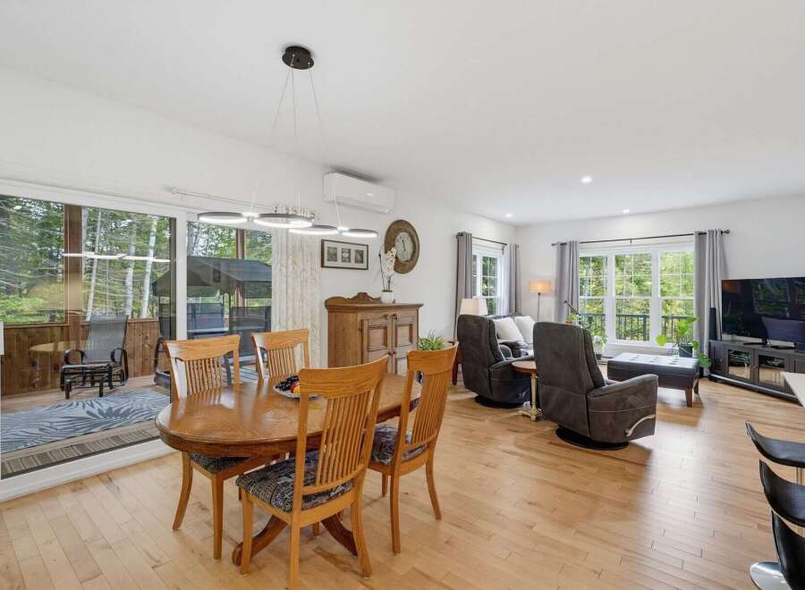 This open-concept living and dining area boasts a large wooden dining table perfect for family meals, complemented by comfortable seating and a modern chandelier.