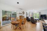 This open-concept living and dining area boasts a large wooden dining table perfect for family meals, complemented by comfortable seating and a modern chandelier.