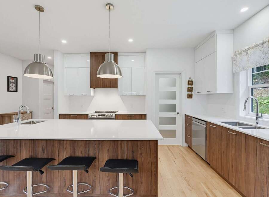 Experience modern luxury in this stunning kitchen featuring a spacious island with waterfall countertops and rich wood cabinetry.