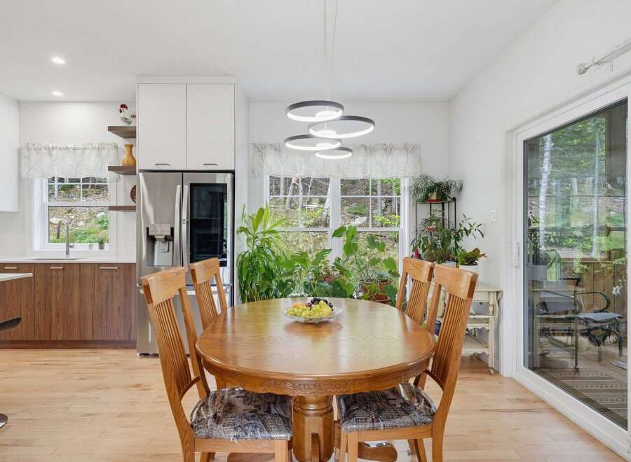 This bright and airy kitchen and dining area features a spacious wooden dining table perfect for family meals, complemented by a modern chandelier.