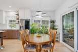 This bright and airy kitchen and dining area features a spacious wooden dining table perfect for family meals, complemented by a modern chandelier.