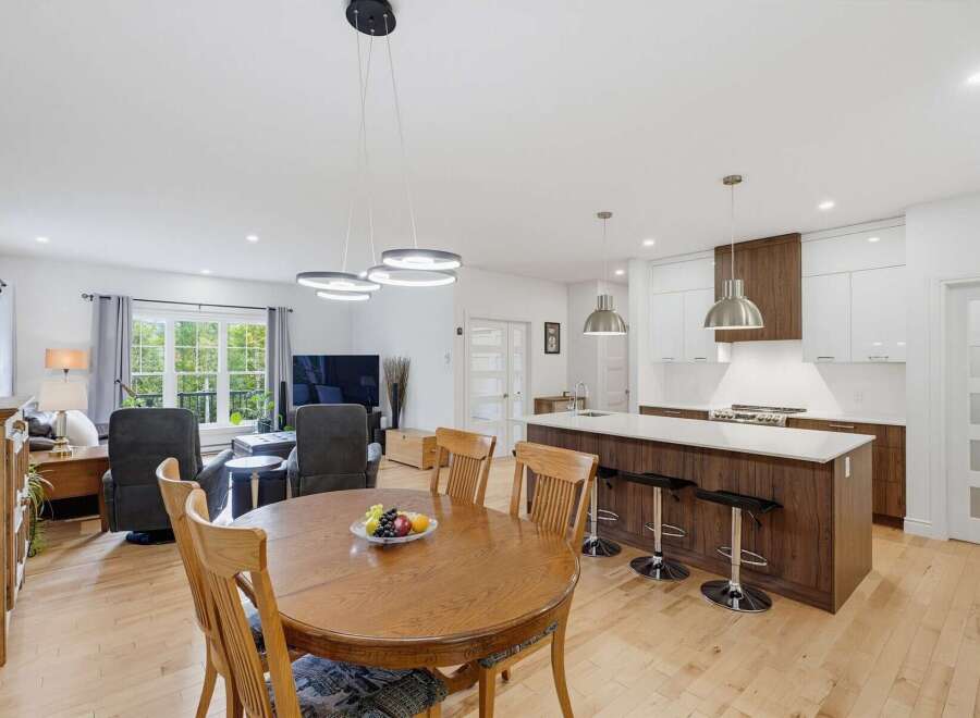 Experience modern living in this open-concept home featuring a spacious dining area with a wooden table and chairs, perfect for family gatherings.