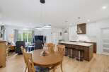 Experience modern living in this open-concept home featuring a spacious dining area with a wooden table and chairs, perfect for family gatherings.