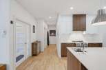 Step into a modern and inviting home featuring a sleek kitchen with white and wood cabinetry, a spacious island with a sink, and stainless steel appliances.