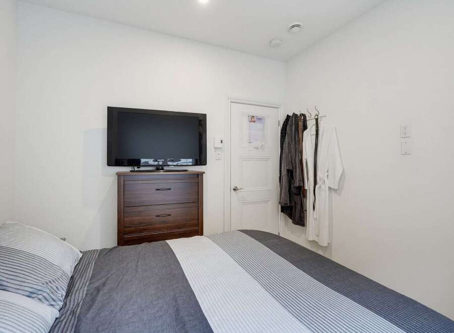 This cozy bedroom features a comfortable bed with striped bedding, a dark wood dresser, and a flat-screen TV for entertainment.