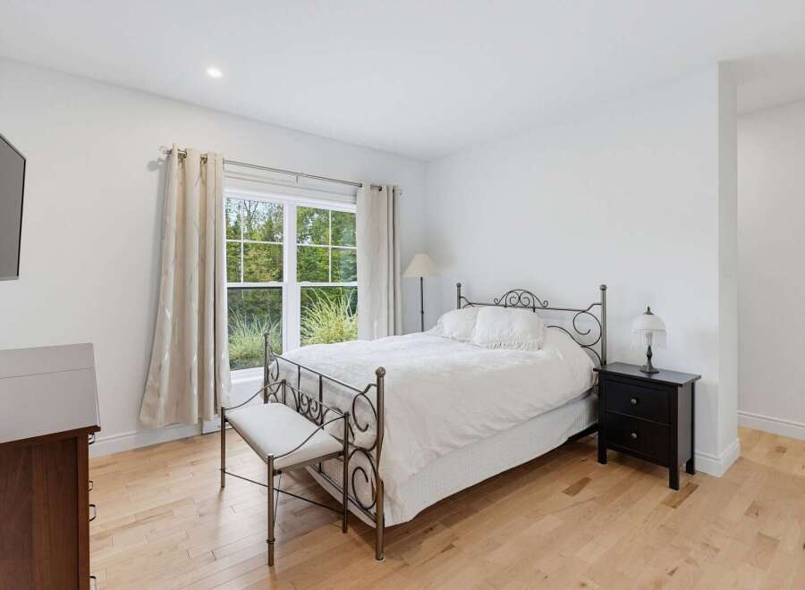This charming bedroom features a comfortable queen-size bed with a wrought iron headboard, complemented by a matching bench at the foot of the bed.