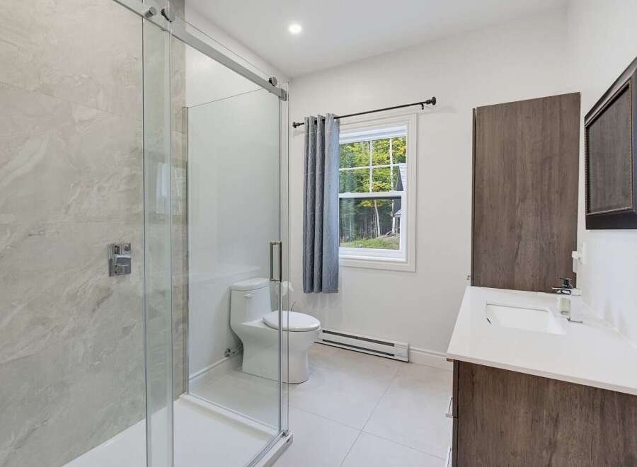 This modern bathroom features a spacious walk-in shower with elegant marble tile and a sleek glass enclosure.