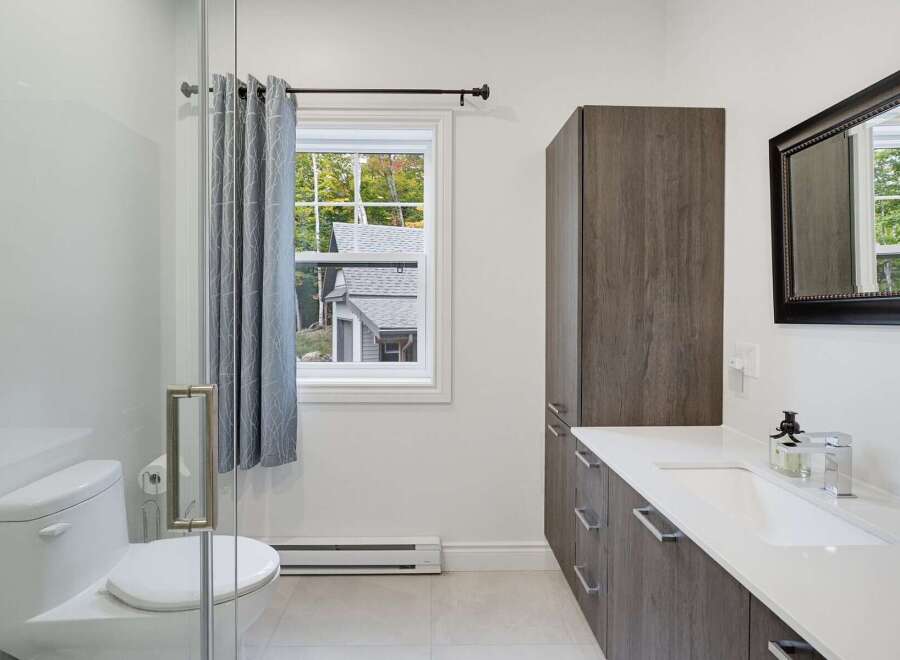 This modern bathroom features a sleek white toilet and a spacious vanity with ample storage.