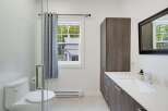This modern bathroom features a sleek white toilet and a spacious vanity with ample storage.