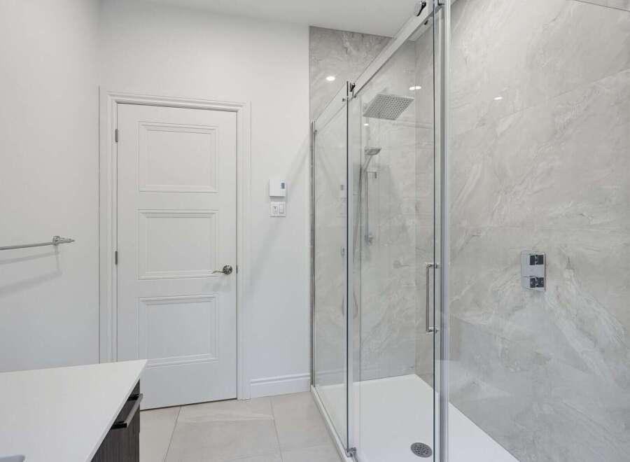 Experience modern luxury in this stunning bathroom, featuring a sleek glass-enclosed shower with a rainfall showerhead and elegant marble-look tiles.