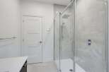 Experience modern luxury in this stunning bathroom, featuring a sleek glass-enclosed shower with a rainfall showerhead and elegant marble-look tiles.