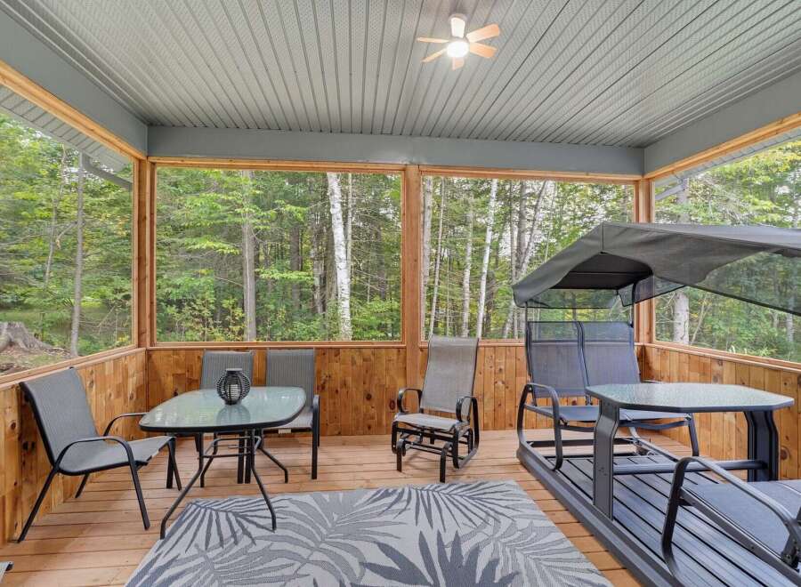 Enjoy the tranquility of nature from this screened-in porch, perfect for outdoor dining or relaxation.