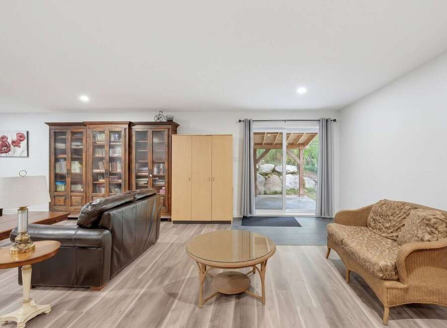 Discover comfortable living in this spacious room featuring a rich brown leather sofa and a charming wicker loveseat, perfect for relaxation.