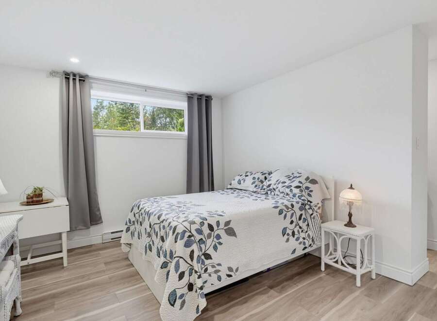 Discover this charming bedroom featuring a comfortable queen-size bed adorned with a beautiful blue and white floral duvet.