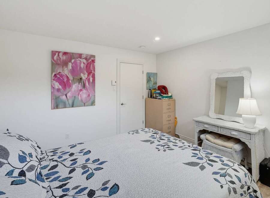 This charming bedroom features a beautiful floral painting above the bed, adding a touch of color and elegance to the space.