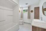 This modern bathroom features a pristine white bathtub and shower combo, perfect for relaxing soaks.