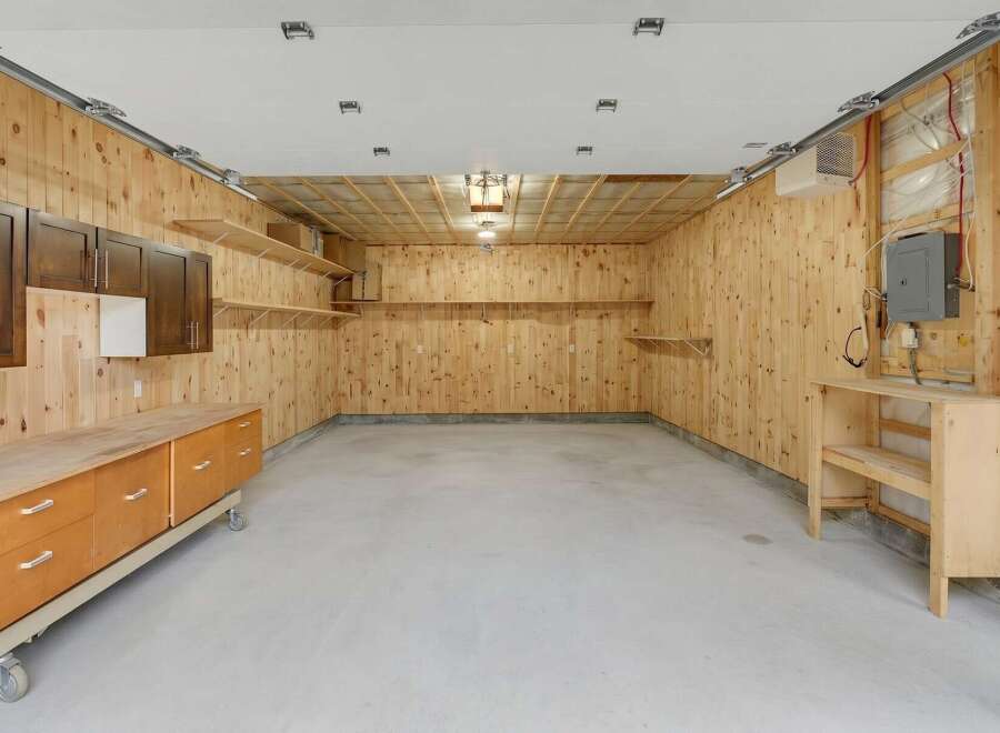 This spacious garage offers ample storage with custom wood cabinetry and multiple shelving units.