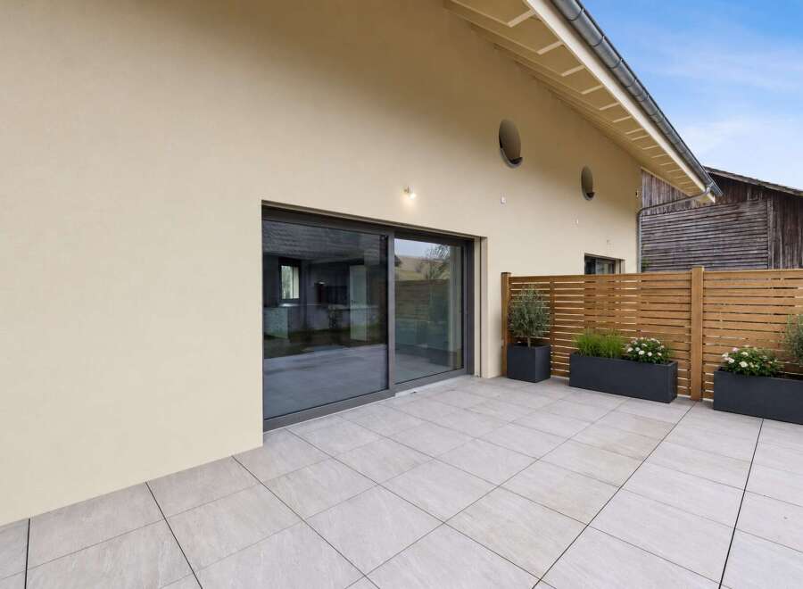 Experience seamless indoor-outdoor living with this modern patio, featuring large sliding glass doors that open onto a spacious tiled area.