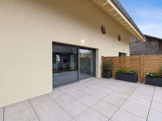 Experience seamless indoor-outdoor living with this modern patio, featuring large sliding glass doors that open onto a spacious tiled area.
