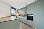 Discover this modern kitchen featuring sleek, sage green cabinetry and a spacious island with a stone countertop.