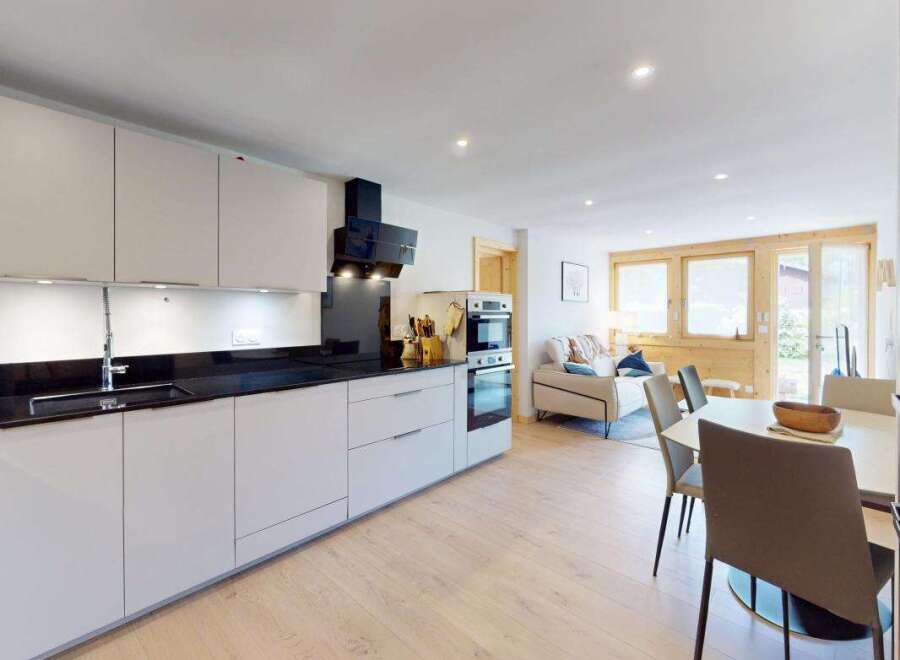Experience modern living in this beautifully appointed kitchen, featuring sleek white cabinetry, a black granite countertop, and integrated appliances.
