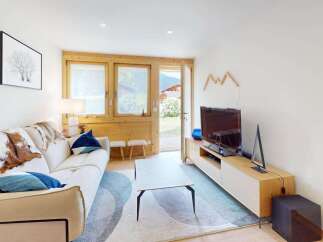 Experience cozy living in this charming mountain retreat, featuring a comfortable sofa adorned with rustic cowhide throws and plush blue pillows.