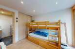 This charming bedroom features a space-saving wooden bunk bed with an integrated pull-out drawer, perfect for maximizing room utility.