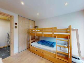 This charming bedroom features a space-saving wooden bunk bed with an integrated pull-out drawer, perfect for maximizing room utility.
