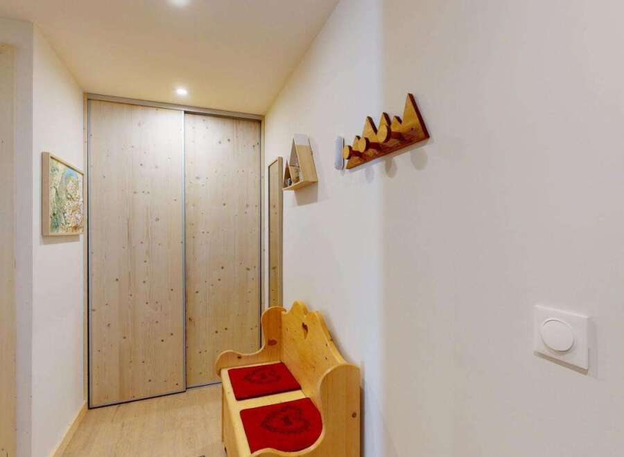 Step into this charming entryway featuring a rustic wooden bench with red cushions, perfect for a cozy welcome.