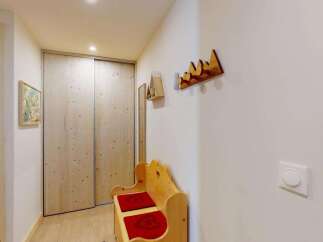Step into this charming entryway featuring a rustic wooden bench with red cushions, perfect for a cozy welcome.