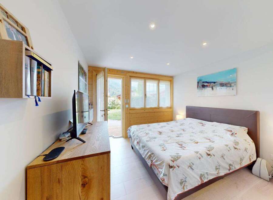 Experience comfort and style in this beautifully appointed bedroom, featuring a spacious bed with a unique patterned duvet and a modern entertainment center.