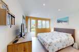 Experience comfort and style in this beautifully appointed bedroom, featuring a spacious bed with a unique patterned duvet and a modern entertainment center.
