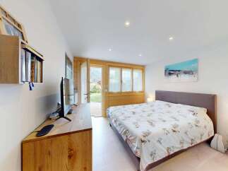 Experience comfort and style in this beautifully appointed bedroom, featuring a spacious bed with a unique patterned duvet and a modern entertainment center.