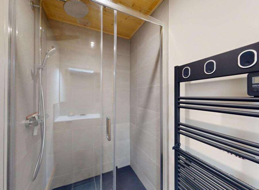 Experience modern comfort in this stylish bathroom featuring a sleek glass-enclosed shower with a rainfall showerhead.