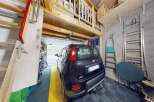 Discover this spacious garage featuring a convenient loft storage area accessible by a sturdy wooden staircase.