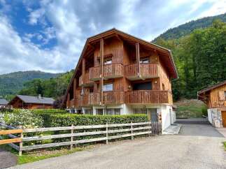 Experience alpine living in this charming wooden chalet, nestled against a backdrop of lush green mountains.