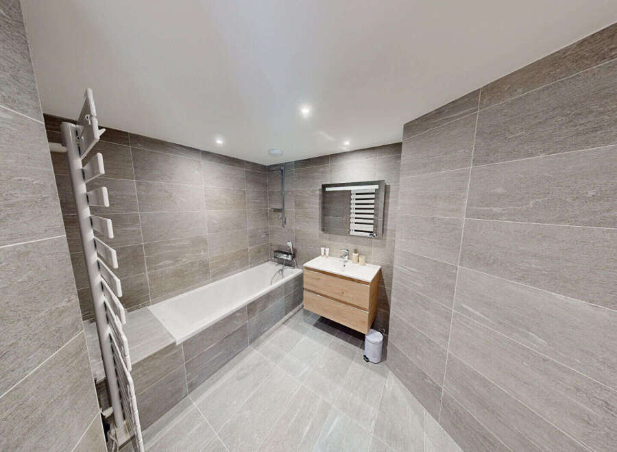 Experience modern luxury in this stunning bathroom, featuring a sleek bathtub and a stylish vanity with ample storage.