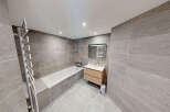 Experience modern luxury in this stunning bathroom, featuring a sleek bathtub and a stylish vanity with ample storage.