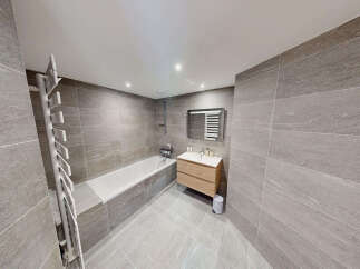 Experience modern luxury in this stunning bathroom, featuring a sleek bathtub and a stylish vanity with ample storage.