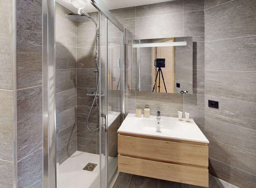 Experience modern luxury in this stunning bathroom featuring a spacious glass-enclosed shower and a sleek vanity with ample storage.