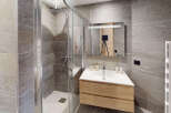 Experience modern luxury in this stunning bathroom featuring a spacious glass-enclosed shower and a sleek vanity with ample storage.