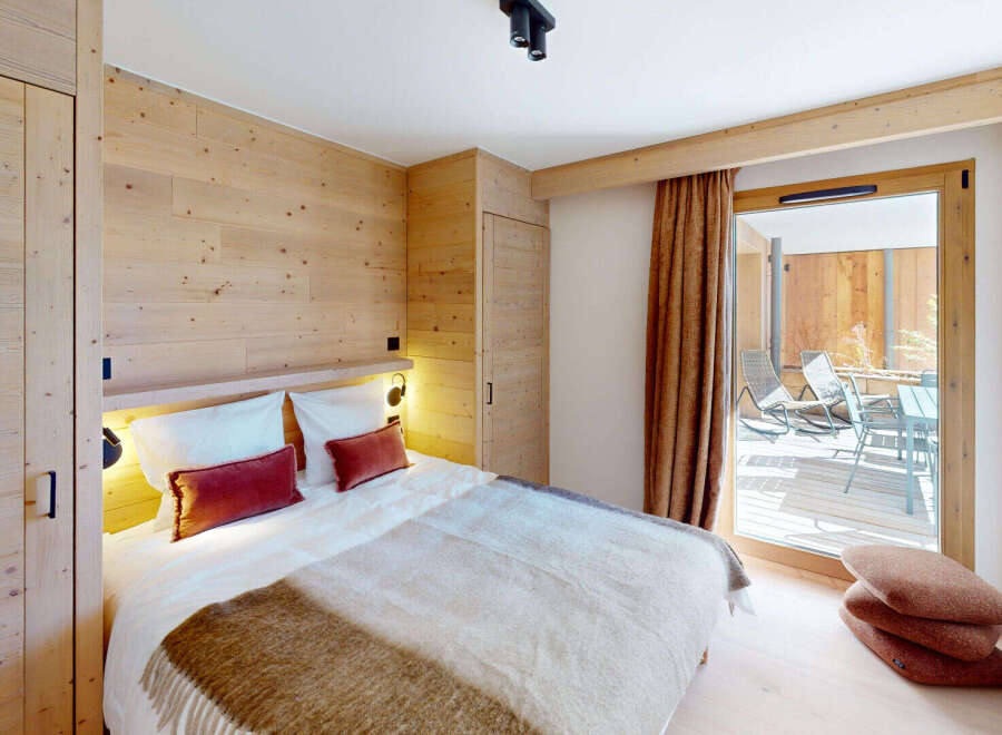 Experience cozy mountain living in this charming bedroom featuring warm wood paneling and a plush king-sized bed.