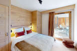 Experience cozy mountain living in this charming bedroom featuring warm wood paneling and a plush king-sized bed.