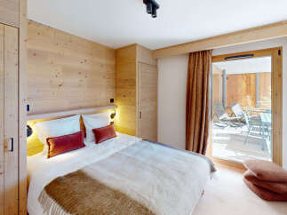 Experience cozy mountain living in this charming bedroom featuring warm wood paneling and a plush king-sized bed.