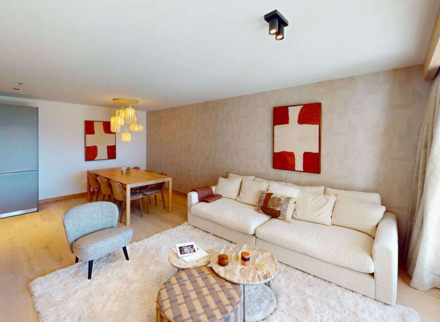 Experience modern living in this spacious open-plan apartment, featuring a stylish living area with a plush sofa and contemporary art.