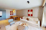 Experience modern living in this spacious open-plan apartment, featuring a stylish living area with a plush sofa and contemporary art.