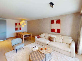 Experience modern living in this spacious open-plan apartment, featuring a stylish living area with a plush sofa and contemporary art.