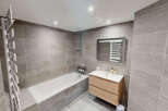 This modern bathroom features a sleek design with large grey stone tiles covering the walls and floor.