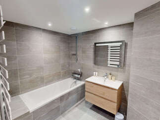 This modern bathroom features a sleek design with large grey stone tiles covering the walls and floor.