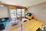 Experience modern mountain living in this beautifully appointed apartment, featuring a plush teal sectional sofa and a warm, wood-paneled accent wall.